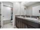 Bathroom with a double vanity, dark wood cabinets, granite counters, and a shower-tub combo with a blue shower curtain at 5426 Rainwood Meadows Dr, Apollo Beach, FL 33572
