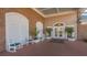Clubhouse entrance featuring white rocking chairs, potted plants, and doors under a porch area, all set on a brick surface at 6501 Stone River Rd # 304, Bradenton, FL 34203