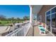 View of the golf course with golf carts, putting green and building with covered porch and white rocking chairs at 6501 Stone River Rd # 304, Bradenton, FL 34203
