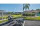 Outdoor grill area featuring a gas grill, seating, tennis court, and buildings on well-manicured lawn under a clear blue sky at 6501 Stone River Rd # 304, Bradenton, FL 34203