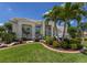 Beautifully landscaped home exterior featuring mature palm trees and a well-manicured lawn with decorative shrubbery at 7031 Scrub Jay Dr, Sarasota, FL 34241