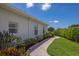Exterior view of home featuring a brick walkway, manicured lawn, and tropical landscaping at 7031 Scrub Jay Dr, Sarasota, FL 34241