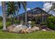The backyard features lush landscaping, a rock garden, and a screened in patio at 7031 Scrub Jay Dr, Sarasota, FL 34241