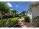 Landscaped side yard with tropical plants, a brick pathway, and lush green lawn at 7031 Scrub Jay Dr, Sarasota, FL 34241