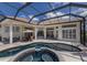 Spacious screened-in pool area with jacuzzi, lush landscaping, and outdoor seating at 7031 Scrub Jay Dr, Sarasota, FL 34241