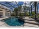 Screened in pool and spa with a waterfall feature and lush landscaping offers a relaxing backyard retreat at 7031 Scrub Jay Dr, Sarasota, FL 34241