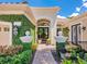 Elegant front entrance with lush greenery, a brick walkway, and a charming lantern fixture at 7229 Lake Forest Gln, Lakewood Ranch, FL 34202