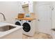 Bright laundry room with sink, butcher block countertop, white cabinets, and machines at 7229 Lake Forest Gln, Lakewood Ranch, FL 34202