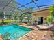 Inviting screened-in pool and spa with lounge chairs and outdoor kitchen area overlooking a serene pond at 7229 Lake Forest Gln, Lakewood Ranch, FL 34202