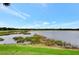 Picturesque view of a pond with aquatic plants, a golf course, and a clear blue sky at 7705 Grand Estuary Trl # 206, Bradenton, FL 34212