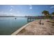 Picturesque waterfront view with pier, sandy beach and lush tropical landscaping on a sunny day at 8225 Drew St, Englewood, FL 34224