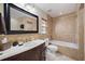 Well-lit bathroom with tiled walls, a bathtub, wood vanity, and a large mirror at 8280 Ibis St, Sarasota, FL 34241