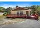 Charming home with a red wooden deck, yellow walls, brown trim, and mature trees in the background at 8280 Ibis St, Sarasota, FL 34241