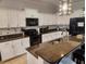 Modern kitchen featuring white cabinets, dark appliances, barstool seating, and decorative lighting at 9011 Hammock Edge Pl, Bradenton, FL 34212