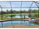 Scenic backyard with a screened-in pool, spa, and a view of the serene pond at 9011 Hammock Edge Pl, Bradenton, FL 34212
