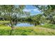 Peaceful backyard pond view with lush green grass and mature trees and vegetation at 9238 13Th Avenue Nw Cir, Bradenton, FL 34209