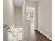 Hallway with hardwood floors, staircase with modern railing, and view into a brightly lit room at 8711 Palmer Park Cir, Sarasota, FL 34238