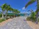 Charming blue home featuring lush, mature landscaping and a brick driveway, perfect for curb appeal at 10016 Spoonbill E Rd, Bradenton, FL 34209