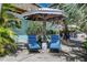 Backyard with blue beach chairs under a shady umbrella, perfect for relaxing near a quaint blue home at 104 29Th St # 3, Holmes Beach, FL 34217