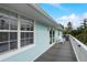 Light blue siding house with large windows, a gray deck, and white outdoor furniture under a blue sky at 104 29Th St # 3, Holmes Beach, FL 34217