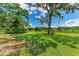 Expansive backyard overlooks a picturesque pond and has a charming bench under a tree at 1103 134Th E St, Bradenton, FL 34212