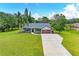 Well-maintained home with a long concrete driveway and lush lawn and tropical trees at 1103 134Th E St, Bradenton, FL 34212