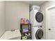 Modern laundry room with stacked washer and dryer, utility sink, and storage shelves at 1103 134Th E St, Bradenton, FL 34212