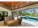 Relaxing screened-in patio features comfortable wicker furniture, pool, and lake views at 1103 134Th E St, Bradenton, FL 34212