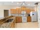 A kitchen showcases wooden cabinets, granite countertops, tile floors, and modern white appliances at 12005 Summer Meadow Dr, Lakewood Ranch, FL 34202