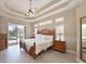 Spacious primary bedroom features a tray ceiling, a ceiling fan, and a sliding glass door leading to the pool area at 15451 27Th E Ct, Parrish, FL 34219