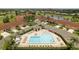 Aerial view of a pristine community pool, well-maintained neighborhood, and a peaceful pond in the distance at 1714 Fairway Trce, Palmetto, FL 34221