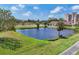 Beautiful pond view surrounded by lush landscaping and mature trees with a building in the background at 1714 Fairway Trce, Palmetto, FL 34221