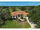 Stunning home features a red front door, tile roof, lush landscaping, and a long driveway leading to a three-car garage at 2183 Muskogee Trl, Nokomis, FL 34275