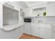 All-white kitchen with a microwave, open shelving, and a pass-through window to the living area at 236 Harbor S Dr # 205, Venice, FL 34285