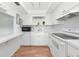 All-white kitchen with a microwave, open shelving, and a pass-through window to the living room at 236 Harbor S Dr # 205, Venice, FL 34285