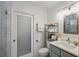 Bright bathroom featuring a gray vanity, shelving unit, and a glass-enclosed shower at 322 35Th Ne Ave, St Petersburg, FL 33704