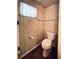 A simple bathroom with a standard white toilet, wood-paneled walls, and a small window at 3221 Sweet Bay Ter, Sarasota, FL 34237