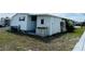 An exterior view of a bright white mobile home showing the utility area and small windows at 3221 Sweet Bay Ter, Sarasota, FL 34237
