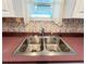 Close-up of a stainless steel kitchen sink with a modern faucet and a window at 3221 Sweet Bay Ter, Sarasota, FL 34237