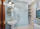 Charming bathroom featuring a pedestal sink, oval mirror, and built-in shelving for storage at 340 Gulf Of Mexico Dr # 124, Longboat Key, FL 34228