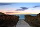 Tranquil sunset view showcasing a sandy walkway leading to the beach and ocean, framed by vibrant vegetation at 340 Gulf Of Mexico Dr # 124, Longboat Key, FL 34228