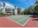 Outdoor tennis court next to tropical vegetation and a building, offering recreational opportunities at 340 Gulf Of Mexico Dr # 124, Longboat Key, FL 34228