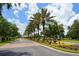 Well-maintained community entrance featuring a brick-paved road, palm trees, fountain, and colorful flowerbeds at 3847 Little Country Rd, Parrish, FL 34219