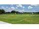 Personal practices golf swing on a well-maintained driving range surrounded by lush greenery and a clear blue sky at 3847 Little Country Rd, Parrish, FL 34219