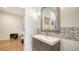 Well-lit bathroom with a modern vanity, decorative mirror, and tile accents with a glimpse into an adjacent room at 404 S Shore Dr, Sarasota, FL 34234