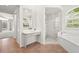 Bathroom featuring a glass enclosed shower, soaking tub, and vanity with ample natural light at 4449 Greenfield Ave, Sarasota, FL 34233