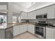 Well-lit kitchen featuring white cabinets, granite countertops, and stainless steel appliances at 4449 Greenfield Ave, Sarasota, FL 34233