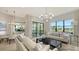 Bright living room featuring large windows with a water view, and neutral toned furniture beneath a modern light fixture at 5715 Inspiration Ter, Bradenton, FL 34210