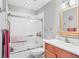 Modern bathroom featuring a glass-enclosed shower-tub combo and a wood vanity at 6414 Sun Eagle Ln, Bradenton, FL 34210