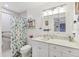 Well-lit bathroom with a white vanity, toilet, and shower-tub combo with a colorful curtain at 6414 Sun Eagle Ln, Bradenton, FL 34210